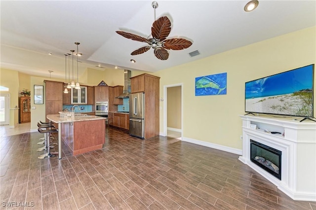 1368 Grebe Dr, Punta Gorda, FL 33950 - kitchen with visible vents, wood finish floors, wall chimney range hood, high end refrigerator, and brown cabinetry