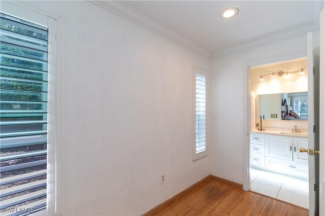 209 Pinehurst Cir, Naples, FL 34113 - unfurnished bedroom with crown molding, baseboards, a sink, light wood-style floors, and ensuite bath