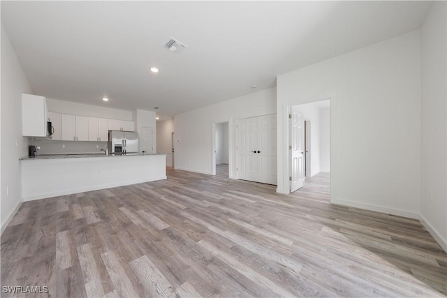 unfurnished living room featuring light wood finished floors, baseboards, visible vents, and recessed lighting
