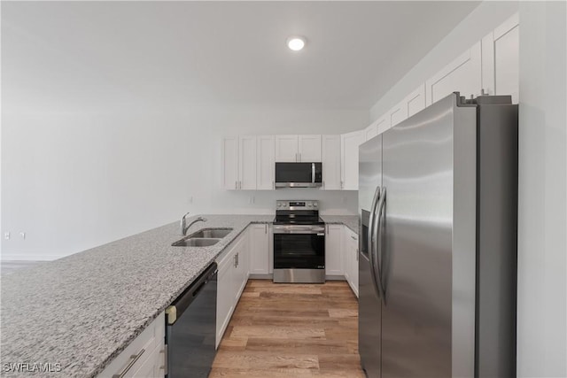 kitchen with white cabinetry, a sink, stainless steel appliances, and light wood-type flooring