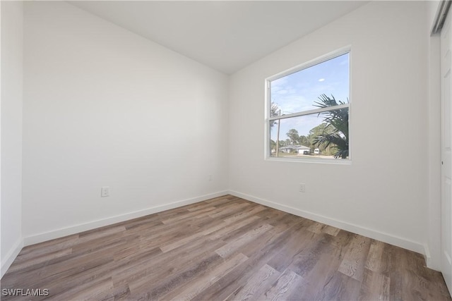 spare room featuring baseboards and wood finished floors