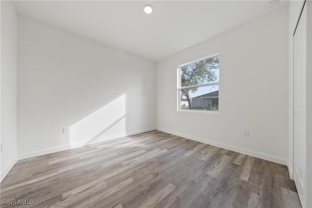 spare room with baseboards and wood finished floors