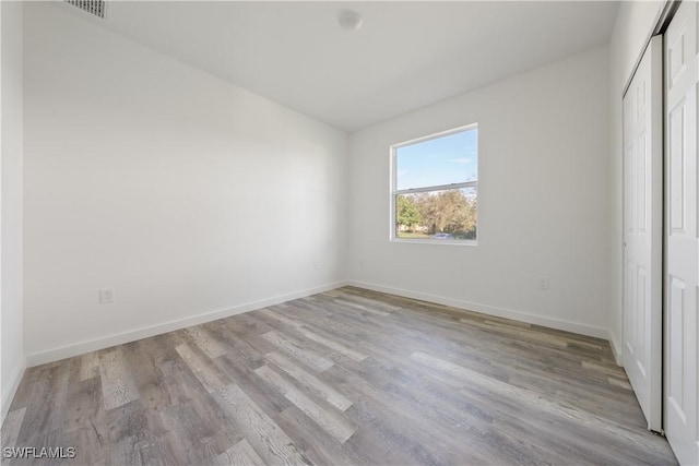 unfurnished bedroom featuring baseboards, visible vents, light wood-style flooring, and a closet