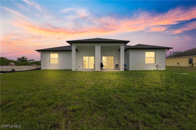 rear view of house featuring stucco siding and a yard