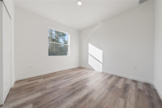 spare room with baseboards, visible vents, and wood finished floors