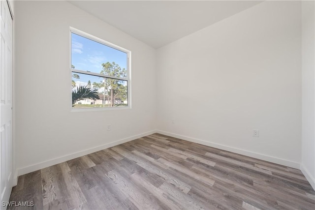 spare room featuring baseboards and wood finished floors