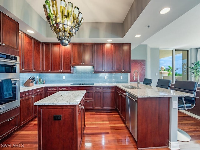 5051 Pelican Colony Blvd Unit 301, Bonita Springs, FL 34134 - kitchen featuring a peninsula, stainless steel appliances, a sink, dark wood-style floors, and backsplash