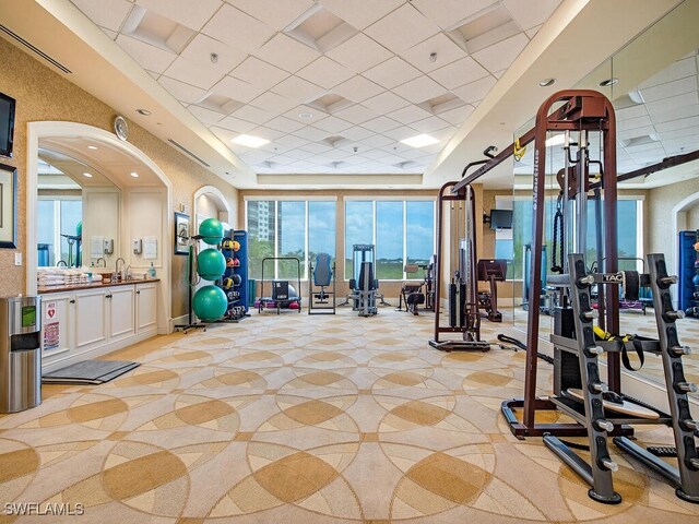 5051 Pelican Colony Blvd Unit 301, Bonita Springs, FL 34134 - exercise room with visible vents, arched walkways, a drop ceiling, a sink, and a tray ceiling