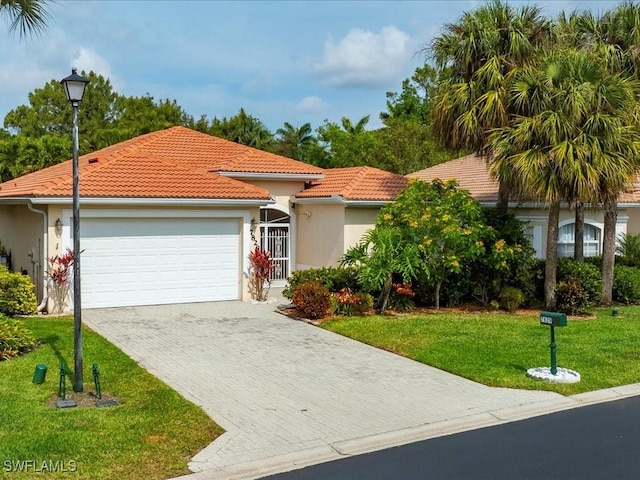 view of front facade featuring driveway, a tile roof, a front yard, an attached garage, and stucco siding