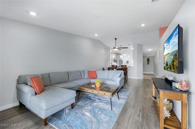 living area featuring ceiling fan, wood finished floors, baseboards, lofted ceiling, and recessed lighting