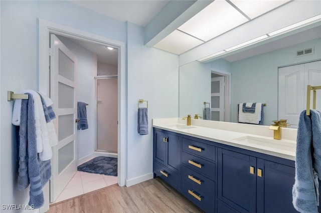 bathroom featuring visible vents, a sink, double vanity, and a shower stall