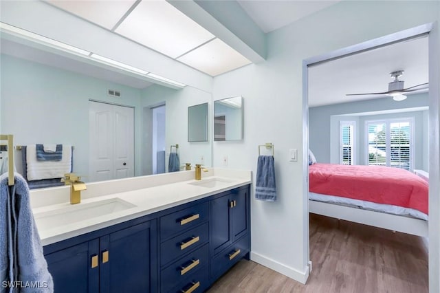 bathroom featuring a sink, baseboards, wood finished floors, and connected bathroom