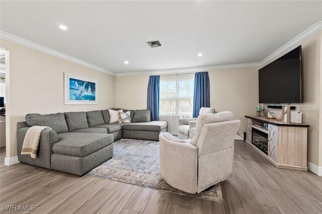 living room with ornamental molding, light wood-style floors, and visible vents