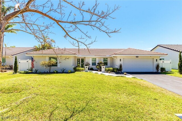 view of front of house with a front yard, fence, an attached garage, aphalt driveway, and a tiled roof