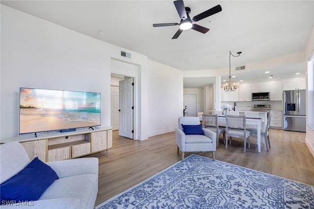 16451 Millstone Cir Unit 101, Fort Myers, FL 33908 - living room featuring light wood-type flooring, ceiling fan, baseboards, and a chandelier