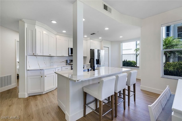 16451 Millstone Cir Unit 101, Fort Myers, FL 33908 - kitchen featuring stainless steel appliances, light wood finished floors, baseboards, a breakfast bar area, and white cabinetry
