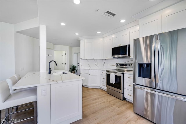 16451 Millstone Cir Unit 101, Fort Myers, FL 33908 - kitchen featuring stainless steel appliances, a sink, white cabinets, recessed lighting, and light wood-style flooring