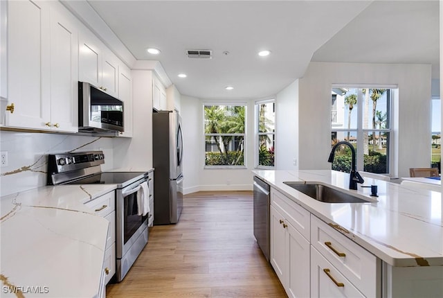 16451 Millstone Cir Unit 101, Fort Myers, FL 33908 - kitchen featuring appliances with stainless steel finishes, a sink, light wood-style flooring, white cabinets, and light stone counters