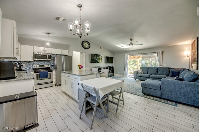 2303 NE 7th Ave, Cape Coral, FL 33909 - kitchen with stainless steel appliances, open floor plan, vaulted ceiling, visible vents, and ceiling fan with notable chandelier