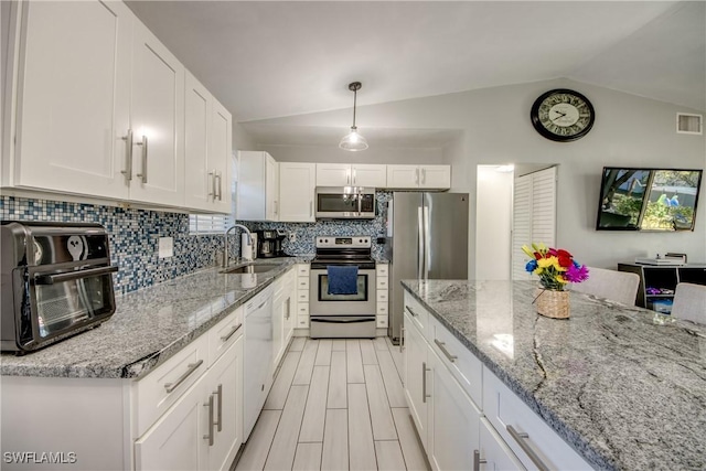 2303 NE 7th Ave, Cape Coral, FL 33909 - kitchen with white cabinets, stainless steel appliances, a sink, tasteful backsplash, and vaulted ceiling