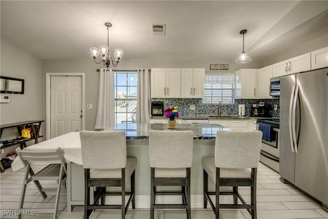 2303 NE 7th Ave, Cape Coral, FL 33909 - kitchen with decorative backsplash, a healthy amount of sunlight, white cabinets, appliances with stainless steel finishes, and visible vents