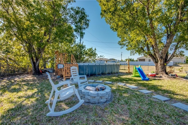2303 NE 7th Ave, Cape Coral, FL 33909 - view of yard with a fire pit, a fenced backyard, and a playground