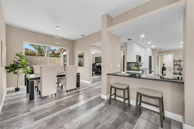 13471 Bridgeford Ave, Bonita Springs, FL 34135 - kitchen featuring decorative light fixtures, stainless steel microwave, baseboards, white cabinets, and wood finished floors