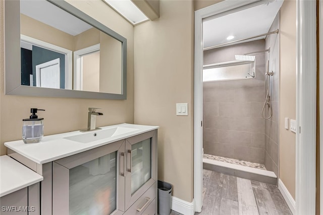 13471 Bridgeford Ave, Bonita Springs, FL 34135 - bathroom featuring vanity, baseboards, tiled shower, and wood finished floors