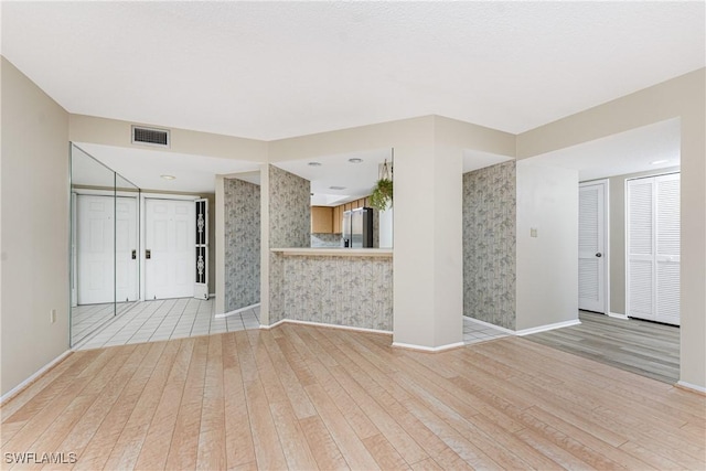 801 Islamorada Blvd Unit 21A, Punta Gorda, FL 33955 - unfurnished living room with light wood-style flooring, baseboards, and wallpapered walls