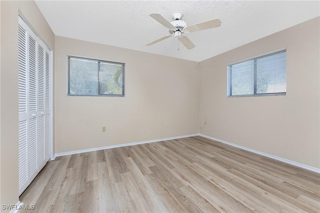 801 Islamorada Blvd Unit 21A, Punta Gorda, FL 33955 - unfurnished bedroom with multiple windows, a closet, light wood finished floors, a textured ceiling, and baseboards