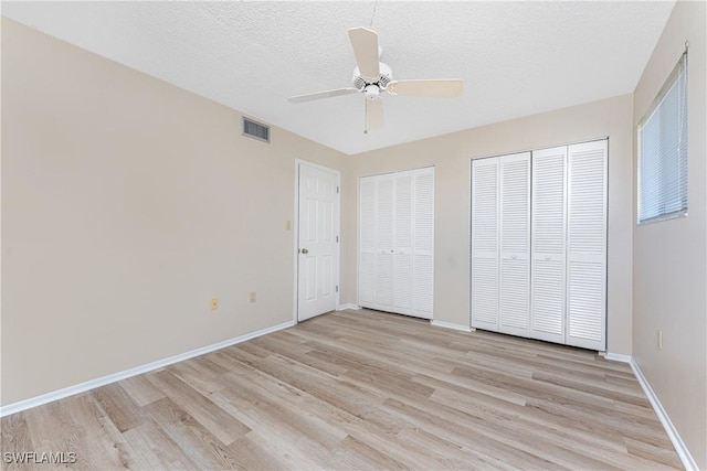801 Islamorada Blvd Unit 21A, Punta Gorda, FL 33955 - unfurnished bedroom with light wood-style floors, two closets, baseboards, a textured ceiling, and a ceiling fan