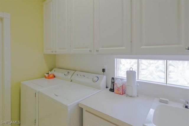 clothes washing area with cabinet space, a sink, and separate washer and dryer