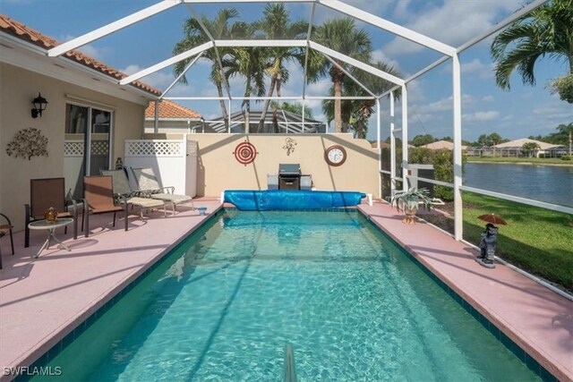 view of pool with a covered pool, a patio, a water view, glass enclosure, and area for grilling