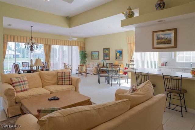 living area featuring a tray ceiling and ceiling fan with notable chandelier