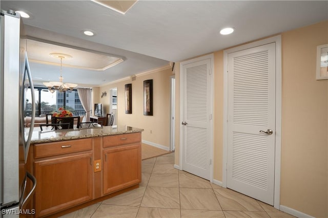 kitchen featuring crown molding, a tray ceiling, baseboards, freestanding refrigerator, and a notable chandelier