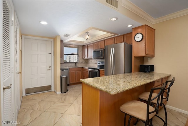 kitchen featuring crown molding, a kitchen bar, appliances with stainless steel finishes, a peninsula, and visible vents