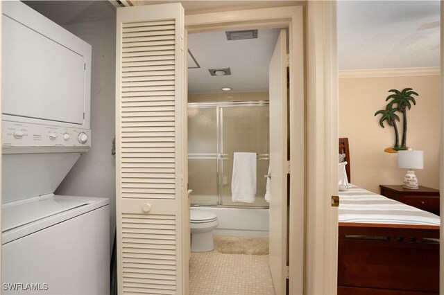 bathroom with tile patterned flooring, ornamental molding, visible vents, stacked washer / dryer, and combined bath / shower with glass door