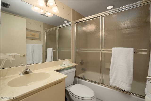 bathroom featuring combined bath / shower with glass door, visible vents, toilet, and vanity