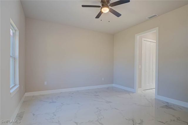 unfurnished room with baseboards, marble finish floor, visible vents, and a ceiling fan