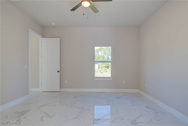 empty room with baseboards, marble finish floor, and a ceiling fan