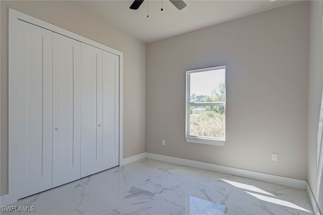 unfurnished bedroom with marble finish floor, baseboards, a closet, and ceiling fan