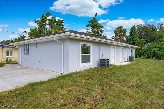 1861 Lillie St, Fort Myers, FL 33916 - view of side of property featuring stucco siding, central air condition unit, a lawn, and a patio area