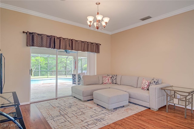 living room with visible vents, crown molding, wood finished floors, baseboards, and a notable chandelier