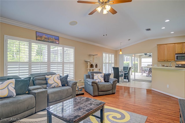 living room featuring a ceiling fan, visible vents, lofted ceiling, ornamental molding, and light wood-style flooring