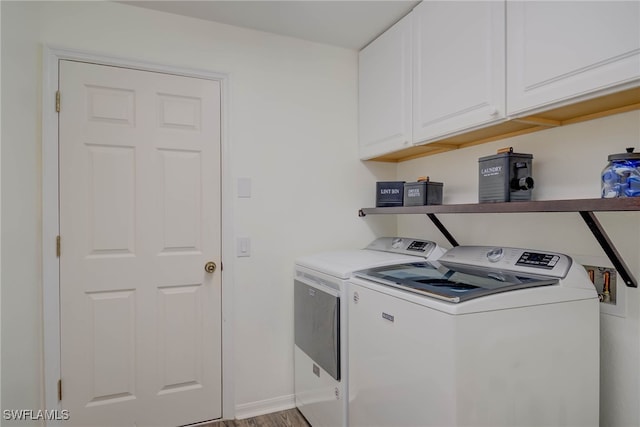 laundry area with light wood-type flooring, cabinet space, and washing machine and dryer
