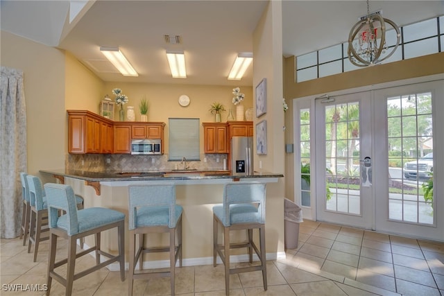 kitchen with brown cabinets, stainless steel appliances, decorative backsplash, and a kitchen bar