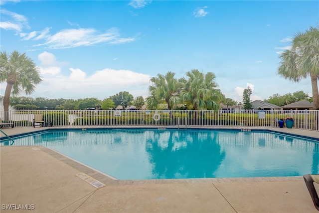community pool with a patio and fence