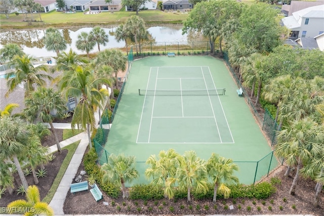 view of sport court featuring fence, a water view, and a residential view