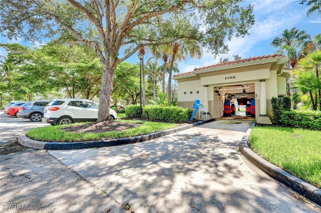 6044 Andros Way, Naples, FL 34119 - view of front of home featuring stucco siding, a garage, a tiled roof, and concrete driveway