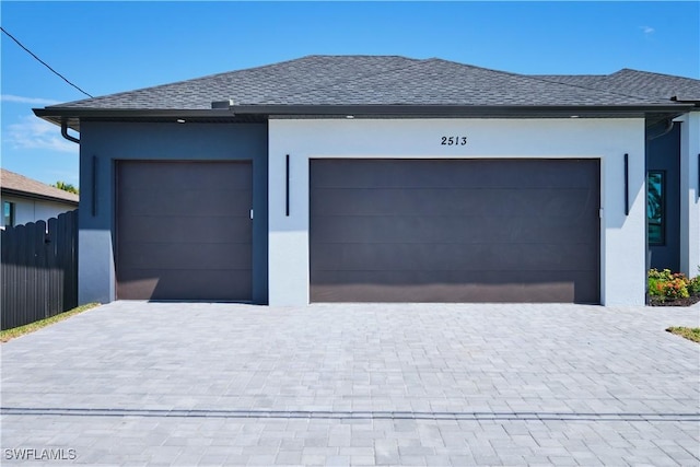 garage featuring fence and decorative driveway